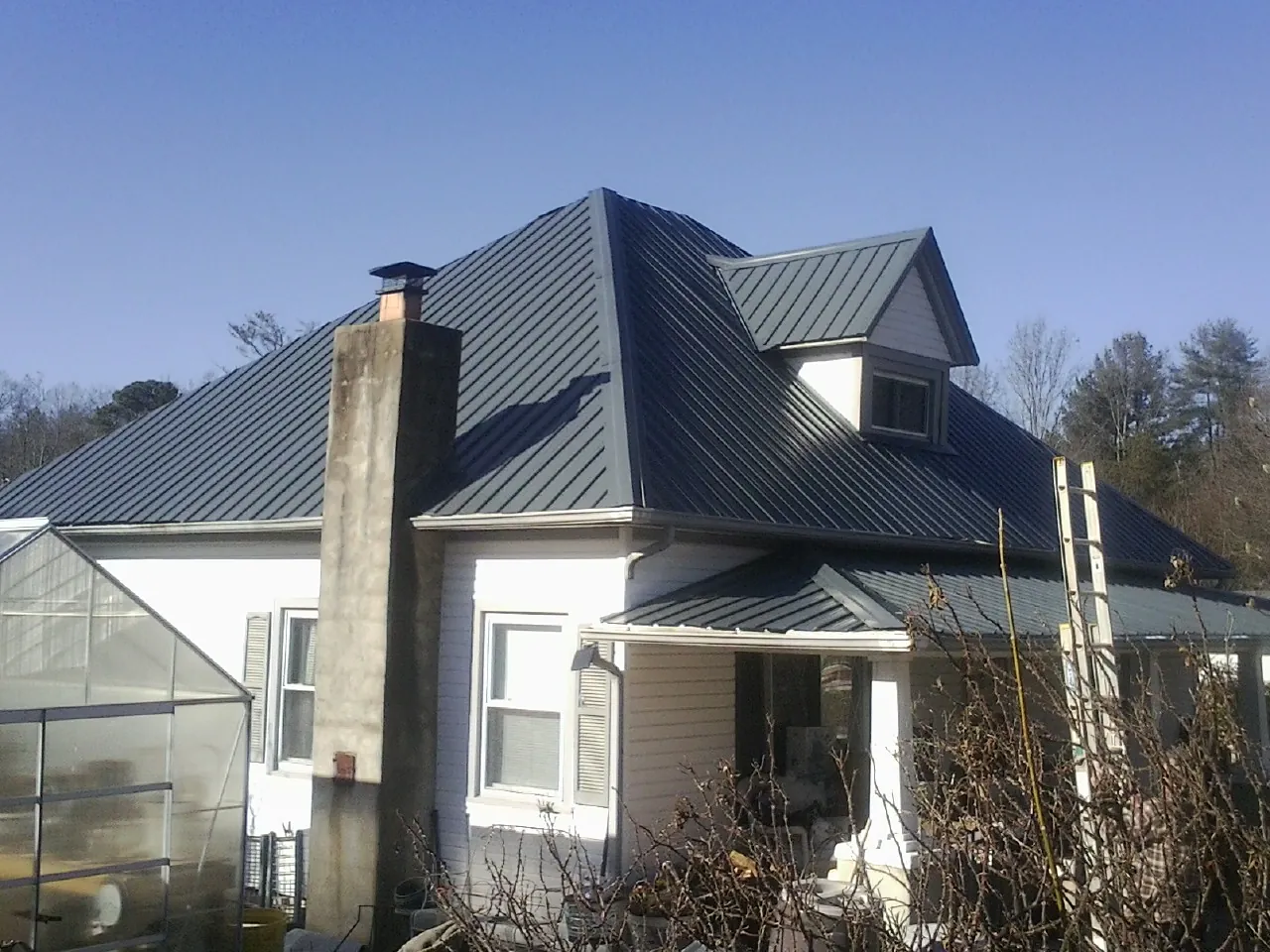 Dark blue standing seam metal roof on a white farmhouse with dormer — Slate & Tile Roof Repair by Roofing Brothers in Bayonne