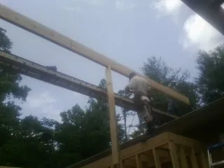 Carpenter setting a ridge beam over a new addition frame — Ice Dam Removal by Roofing Brothers in Bayonne