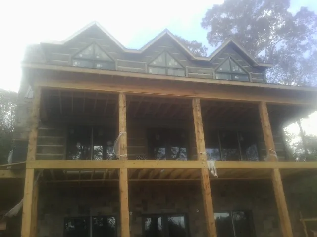 Dormers and porch framing on a large log home under construction — Roof Coating work by our crew in Bayonne