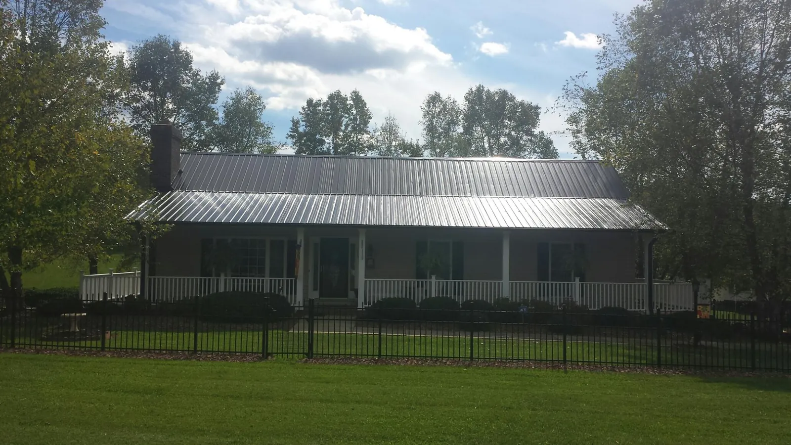 Gray metal roof on a brick ranch with a full width front porch — Gutter Guard Installation work by our crew in Bayonne
