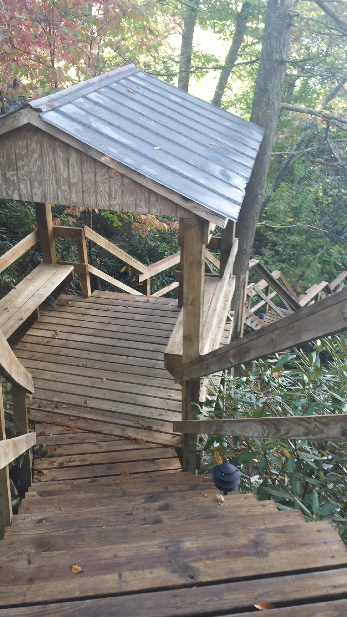 Metal roofed shelter over wooden steps on a wooded walkway — Skylight Repair & Installation work by our crew in Bayonne