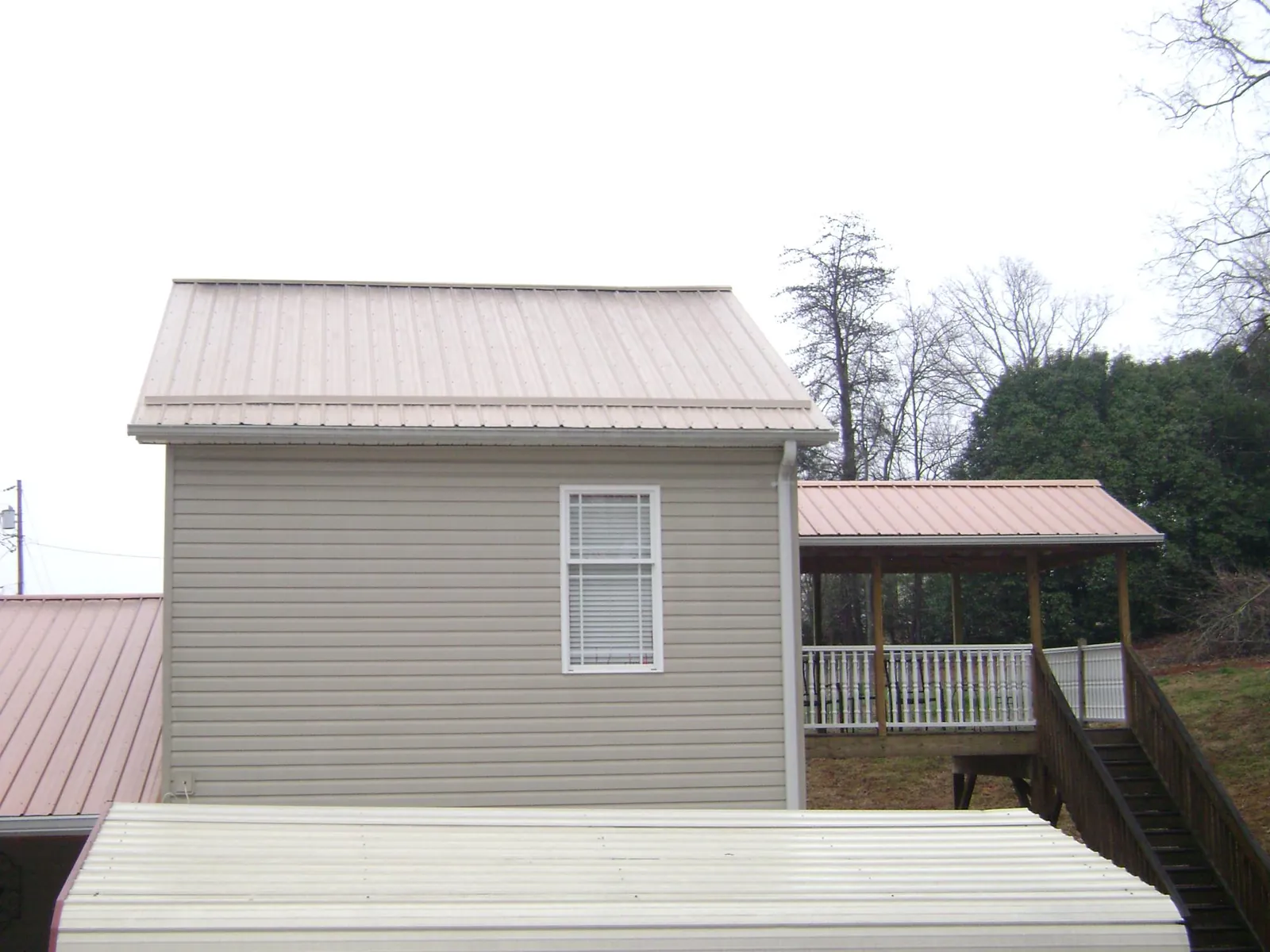 Tan metal roofs on a two story addition and attached porch, from a Roof Replacement job in Bayonne