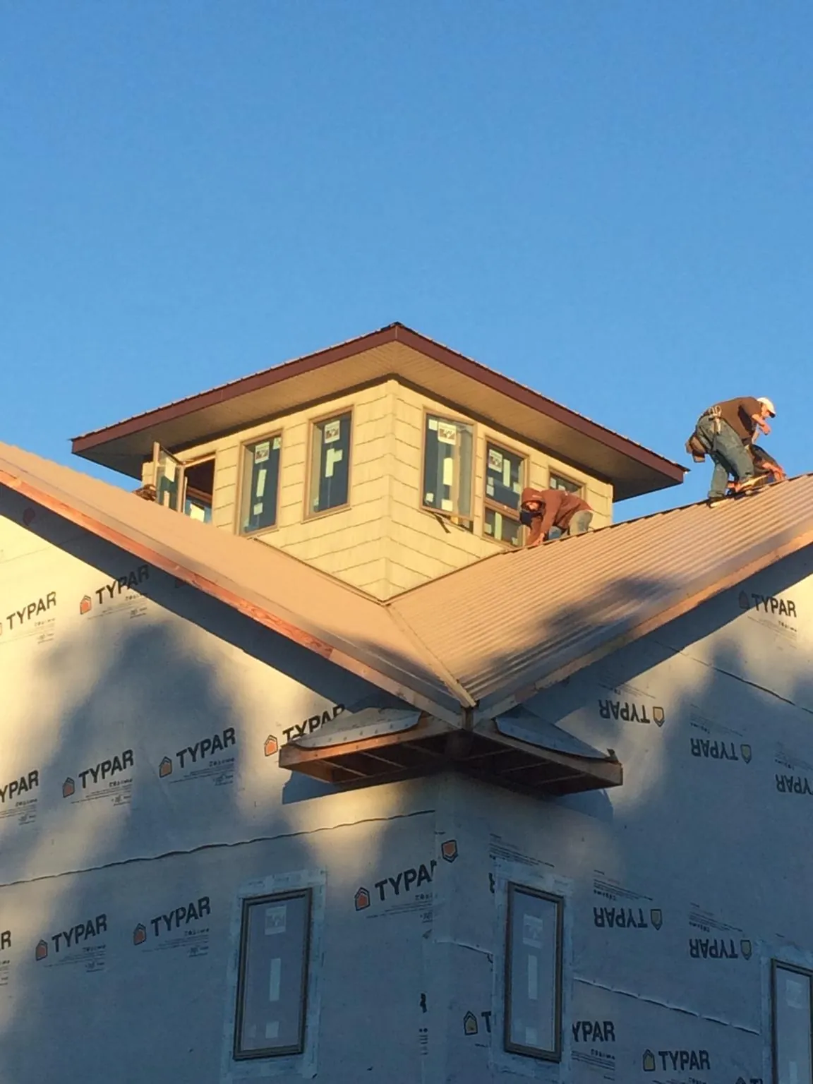 Roofers working around a rooftop cupola on a new metal roof at sunset — Roof Waterproofing in Bayonne by Roofing Brothers